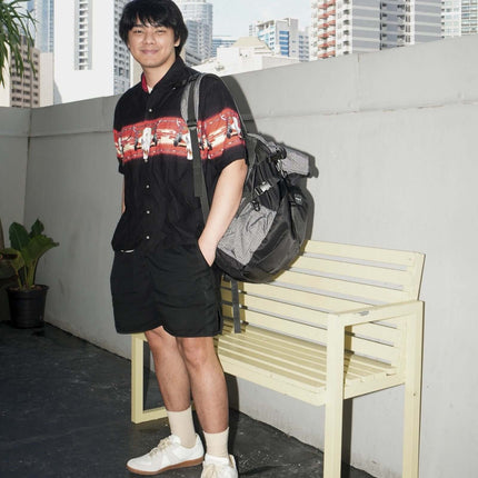 Sora Backpack for Biker, Mountain Climbing worn by a young man in casual attire on a stylish bench.