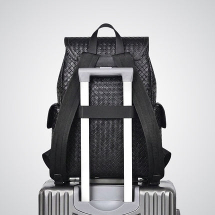 Black woven backpack on a silver suitcase with a white background