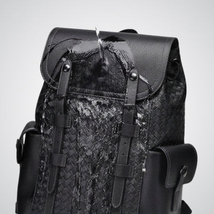 Black woven backpack with leather straps on a light gray background