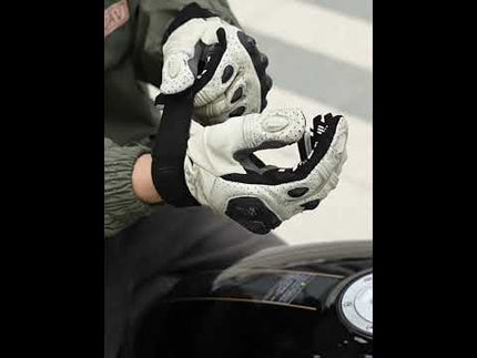 Motorcycle gloves being worn by a rider, showcasing grip and protection features.